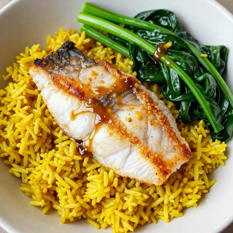 Seared white fish with crispy skin over turmeric rice and wilted greens with ginger sauce
