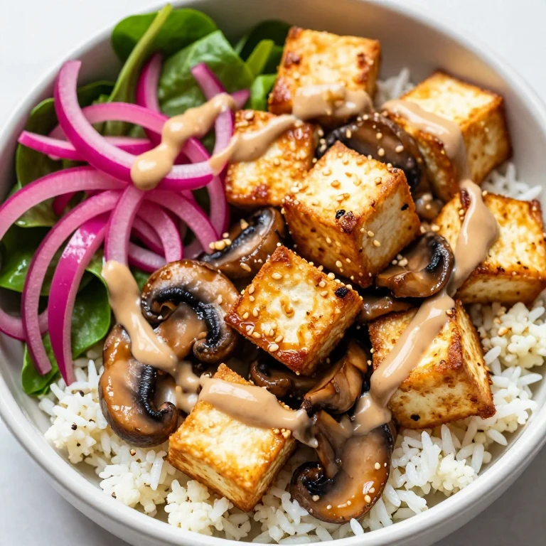 Crispy tofu and mushroom bowl with tahini sauce and pickled onion