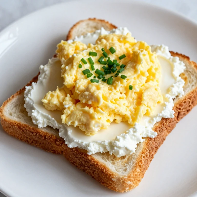 Toast topped with cottage cheese and soft scrambled eggs with chives